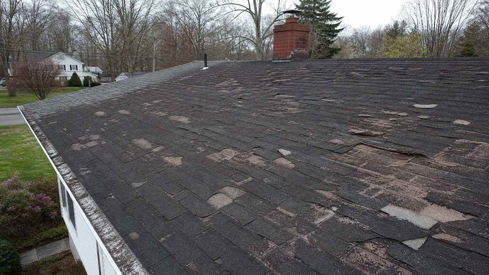 Failing roof with multiple damaged shingle sections