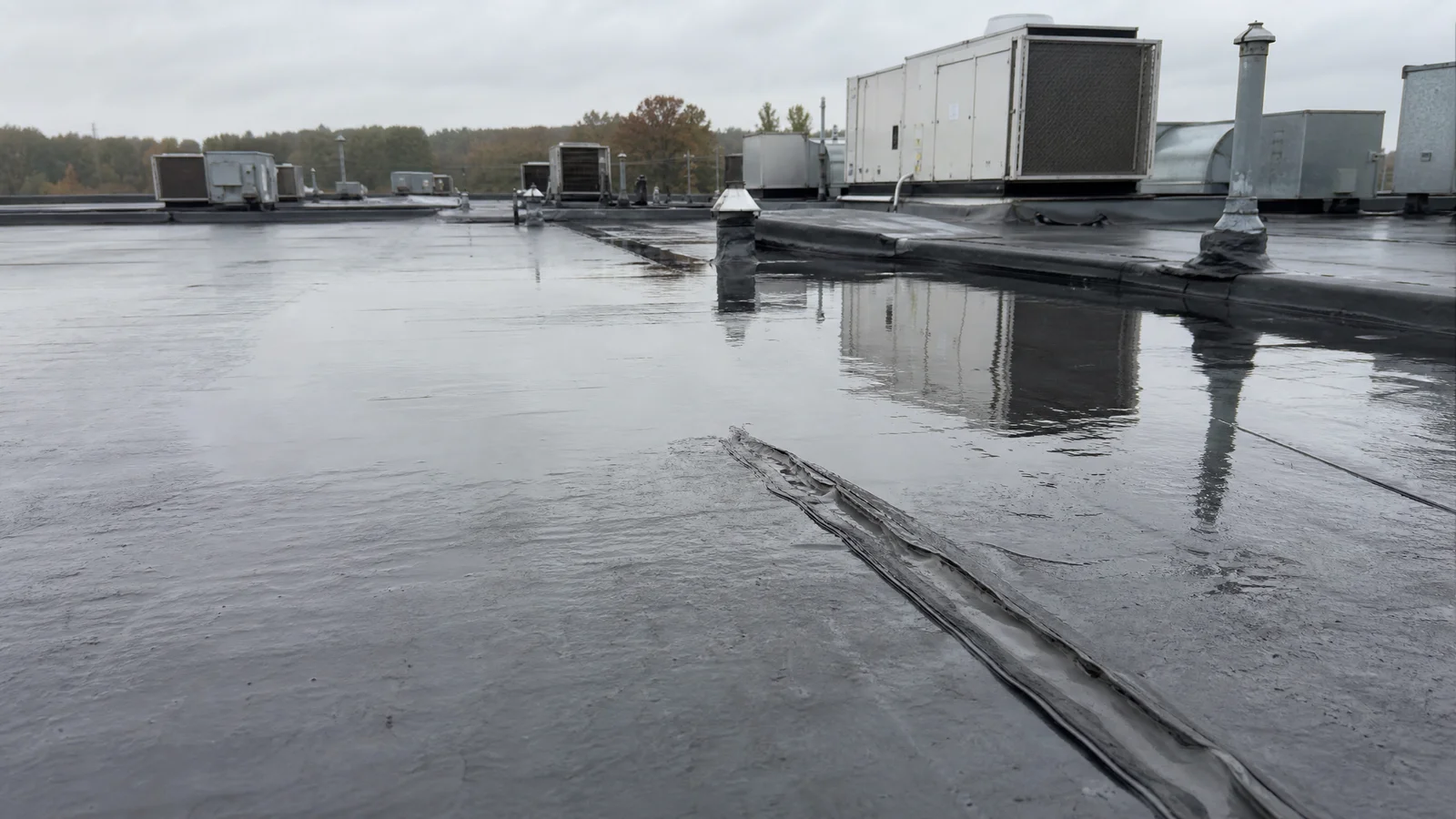 Flat commercial roof with ponding and worn seam