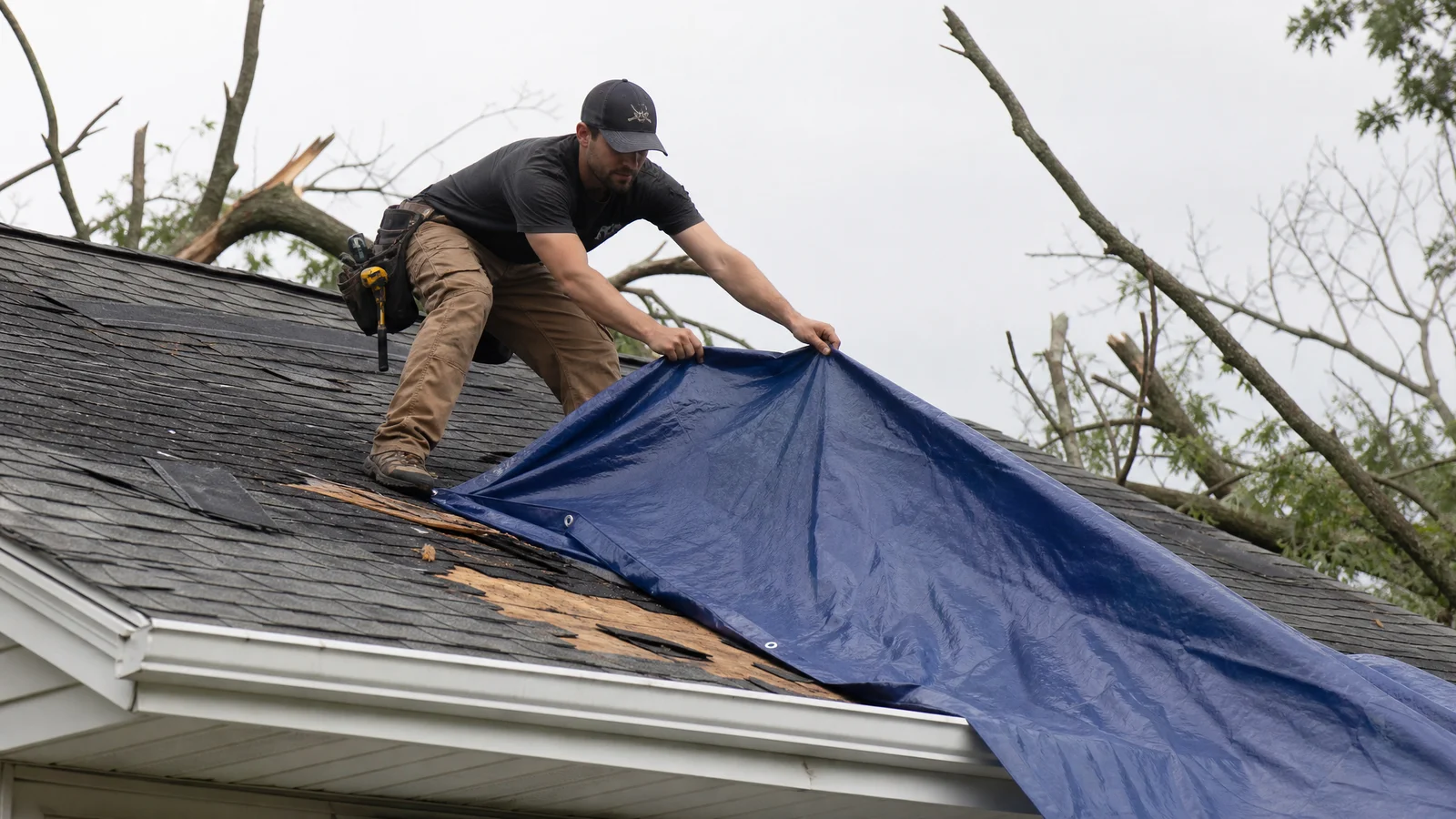 Emergency tarp being installed on storm-damaged roof
